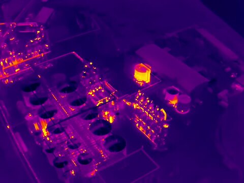 Aerial infrared thermal view of industrial zone with factories and warehouses, in purple and yellow hues
