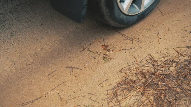 Close up wheels in motion car by sand road. Rotating tyre on dirty road. Automobile offroad