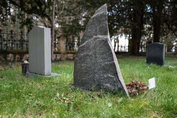 Unusual granite gravestone in the shape of a shark's fin seen at an English cemetery. The granite...