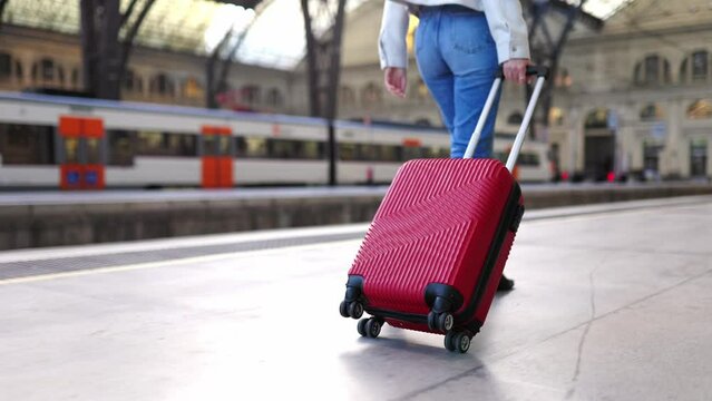 Close up view of casual traveler woman carrying suitcase at train station. Travel and holiday lifestyle concept.