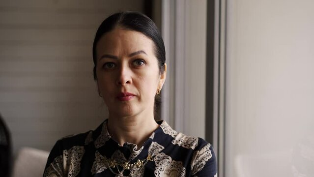 Brunette hair mother worried looking in window, waiting for husbands with kids. Angry mommy stressed staying home alone and feel sadness. Folded hands protestant religion prayer lady