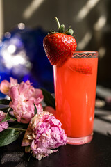 Strawberry juice in a glass on a black background with flowers