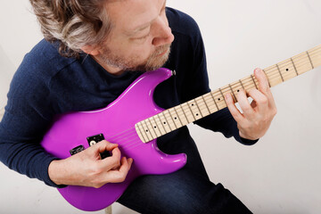 anonymous man practicing guitar sitting down