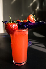 Strawberry juice in a glass on a black background. Selective focus.