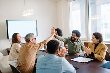 A spirited office team engages in a high-five, highlighting the successful collaboration and...