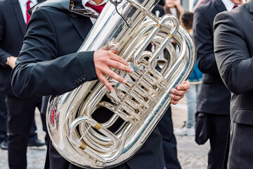 Close-up of musicians playing the tuba, focusing on hands and instruments.
