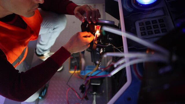 computer mechanic fixing arcade games machine in a recreational room, arcade games operator fixing machines, engineer fixing recreational machine