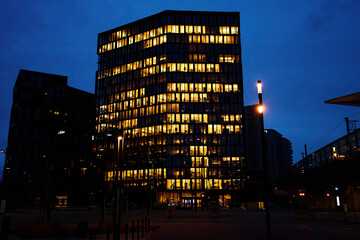 Office building lights up the evening with windows glowing in the dusk, showcasing urban work life after hours