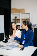 Female discussing new project with Female colleague. Young women talking with young Asian man in office.