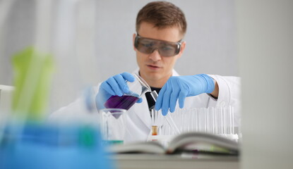 A male chemist holds test tube of glass