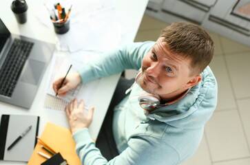 A young designer holds a pen from a tablet in his