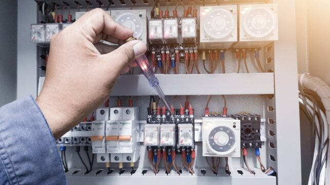 Checking the electrical power on the control panel using a test pen, a repair concept in electrical troubleshooting by an electrical engineer.