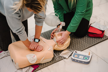 Automated external defibrillator device, AED with training dummy mannequin. Use an automatic defibrillator in conducting basic cardiopulmonary resuscitation of victim. Demonstrating chest compressions