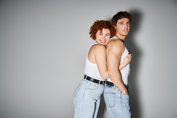 joyful appealing couple in cozy blue jeans hugging warmly and smiling at camera, sexy couple