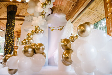 Photo wall decoration of angel wings and white and gold balloons in hall restaurant. Celebration...