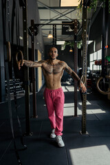 Obraz na płótnie Canvas Chico joven musculado y tatuado posando en gimnasio sin camiseta