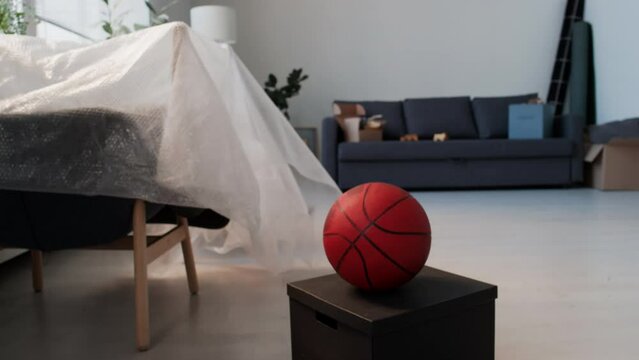 No people shot of basketball on black box in living room with furniture packed in bubble wrap after moving in new house