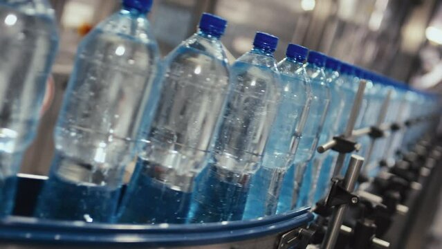 No people Dutch angle footage of row of bottles with still or table water moving on conveyor at bottled water manufacturing plant