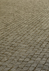 The texture of the paving slab (paving stones) of many small stones of a square shape under bright...