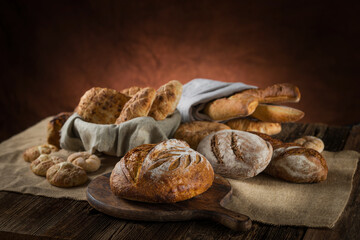 Assortment of baked sourdough bread and bread rolls on wooden table background.