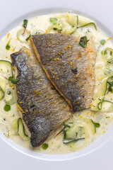 Baked fish with zucchini and dill on a white plate