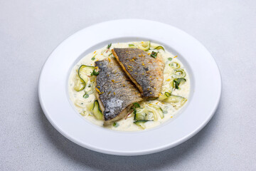 Baked fish with zucchini and dill on a white plate