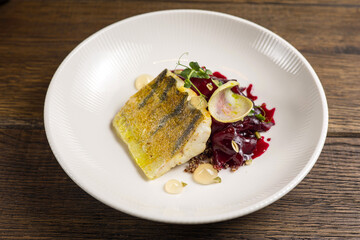 Baked fish with zucchini and dill on a white plate