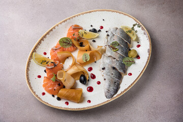 Sliced fish with lemon and olives on a white plate