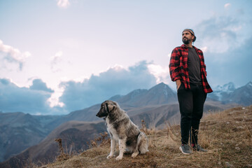 A young man with his dog in the mountains on a hiking trip.