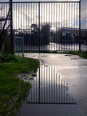 Railings reflected in a puddle in a footpath