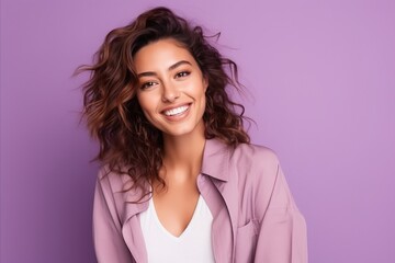 Portrait of a smiling young woman looking at camera over purple background