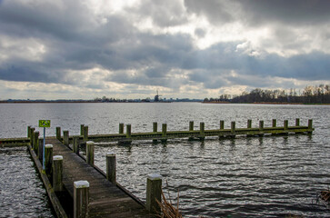 Fototapeta na wymiar Wooden jetty on the bank of the river Rotte in the Netherlands under a dramatic sky