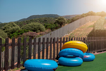 Blue and yellow inflatable wheels against background of wooden fence and nature
