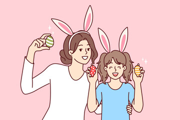 Easter eggs in hands of happy mother and daughter with bunny ears, to celebrate traditional christian holiday. Easter portrait of little girl with nanny or older sister rejoicing in coming of spring