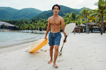 Happy Asian Man Kayaking in Tropical Paradise: Exhilarating Recreational Adventure on Beach with...