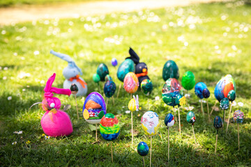 Easter eggs bunnies painted with paints sparkles by children's hands lie lawn sunny spring day park.
