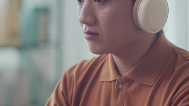 Tilt up shot of Asian male programmer fixing errors in code while sitting at office desk