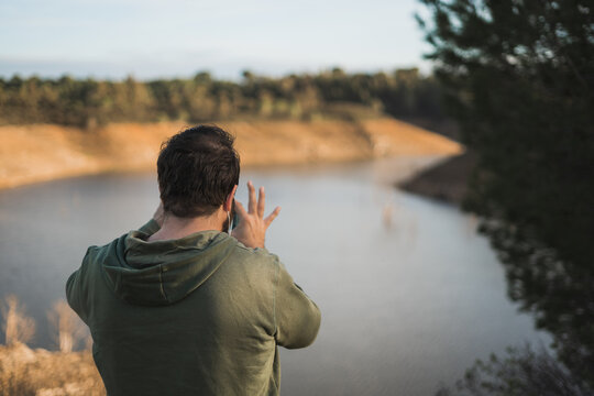Man photographing a lake with cell phone