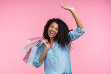 Studio shot of happy smiling beautiful cheerful girl with a bunch of paper bags in hands having fun enjoying shopping, isolated over pastel pink background - 745786728