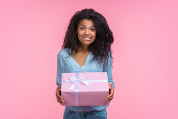 Studio portrait of cute happy girl holding a big present box in her hands excited looking forward to open it