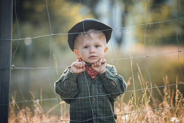 Cute Toddler Kid in Western Cowboy Outfit behind the Wire Fence - 745787127