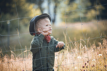 Cute Toddler Kid in Western Cowboy Outfit behind the Wire Fence - 745787198