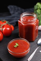 Delicious ketchup on black wooden table. Tomato sauce