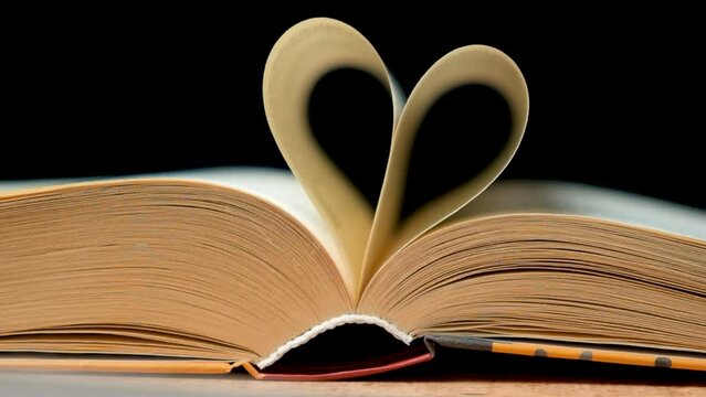 Book pages folded in the shape of a heart on a black background