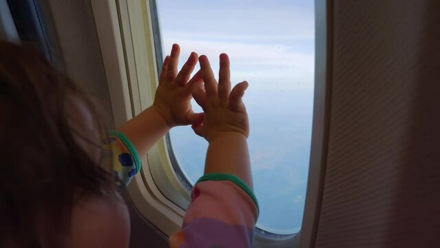 Child's hands reaching out towards the airplane window with a sense of wonder in 4k slow motion 120fps