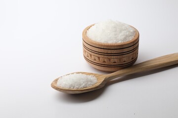 Natural salt in wooden spoon and bowl on white background