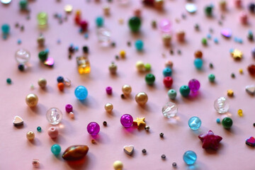 Various colorful beads on bright pink background. Selective focus.