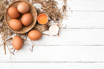 Egg yolk and eggs in bamboo basket and rice straw on vintage white wooden background with copy space, Top view raw eegs or fresh eegs in farm