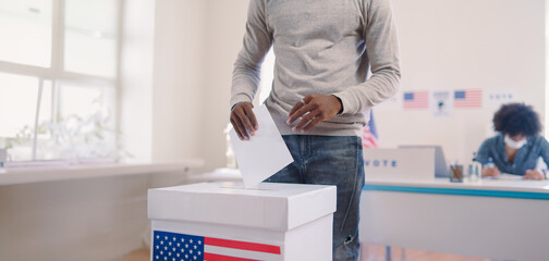 Unrecognizable woman putting her vote in the ballot box, usa elections. Banner with copy space.