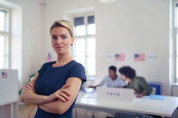 Portrait of female voter filling election ballot paper. US citizen voting in polling place on...